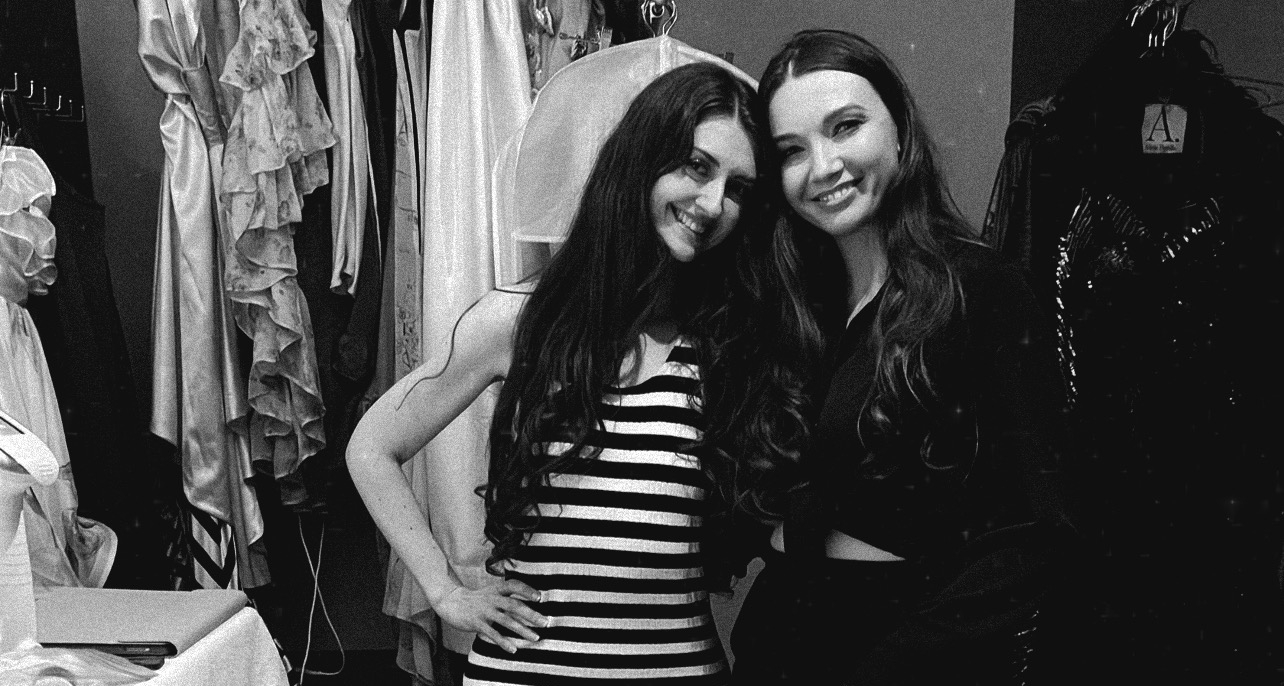Two women smiling together in a dress studio