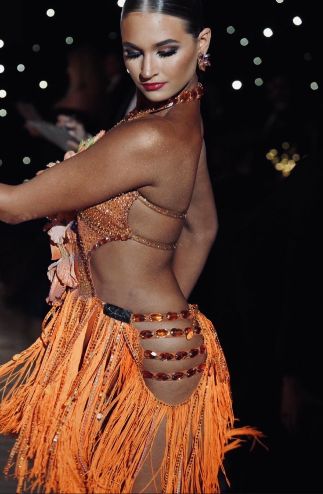 Ballroom dancer in an orange crystal and fringe dress