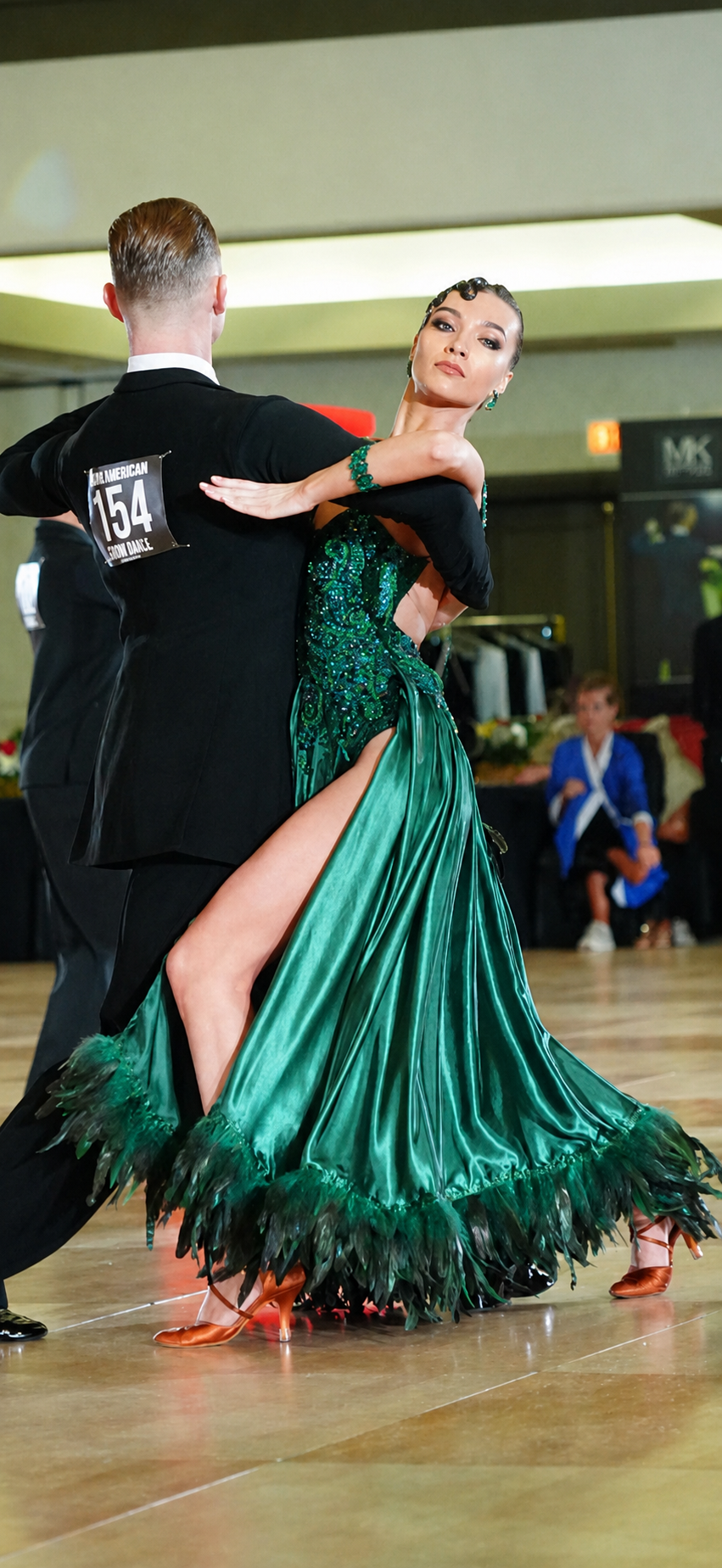 Ballroom dancer wearing the green Emerald gown with her dance partner