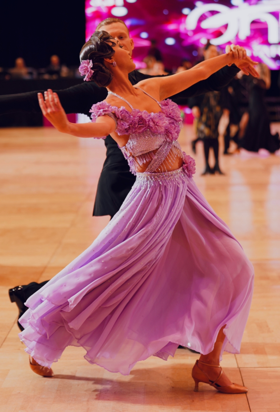 Ballroom dancer moving in the lavender Carnation Veil gown with her dance partner